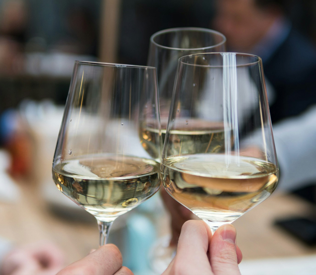 three glasses of white wine cheersing